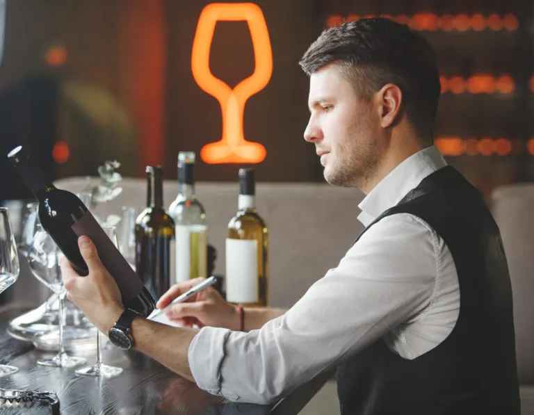 Professional sommelier looks at bottle of expensive wine.